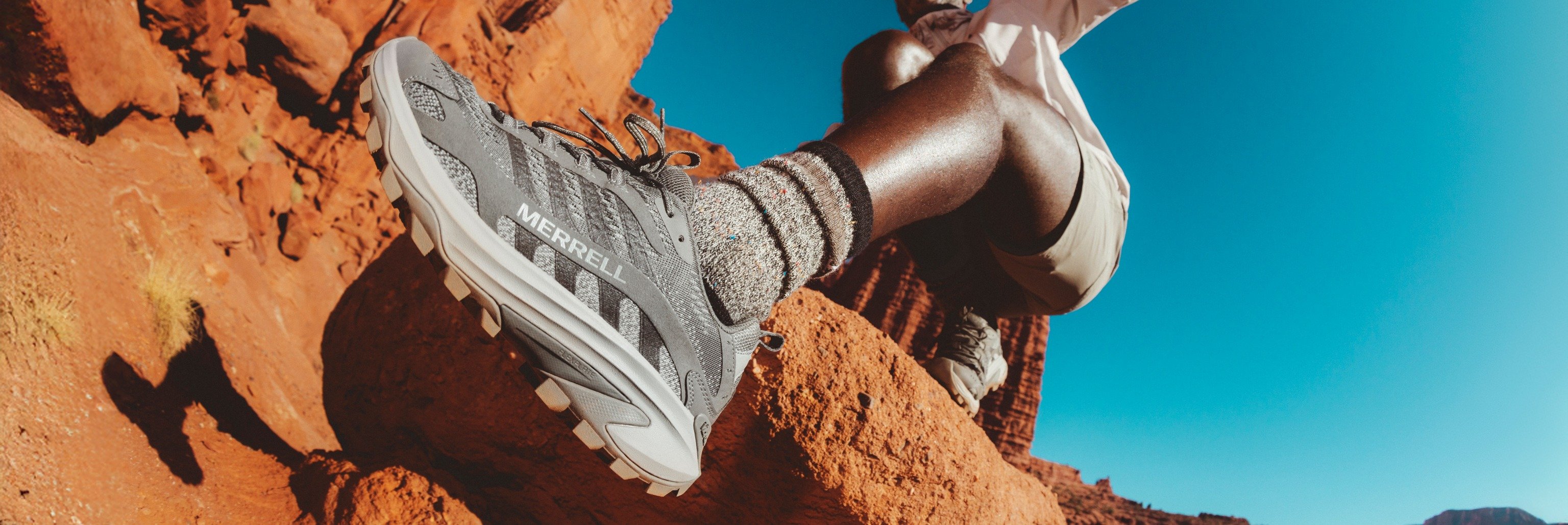 Hiker sitting on red desert rock wearing Merrell hiking shoes